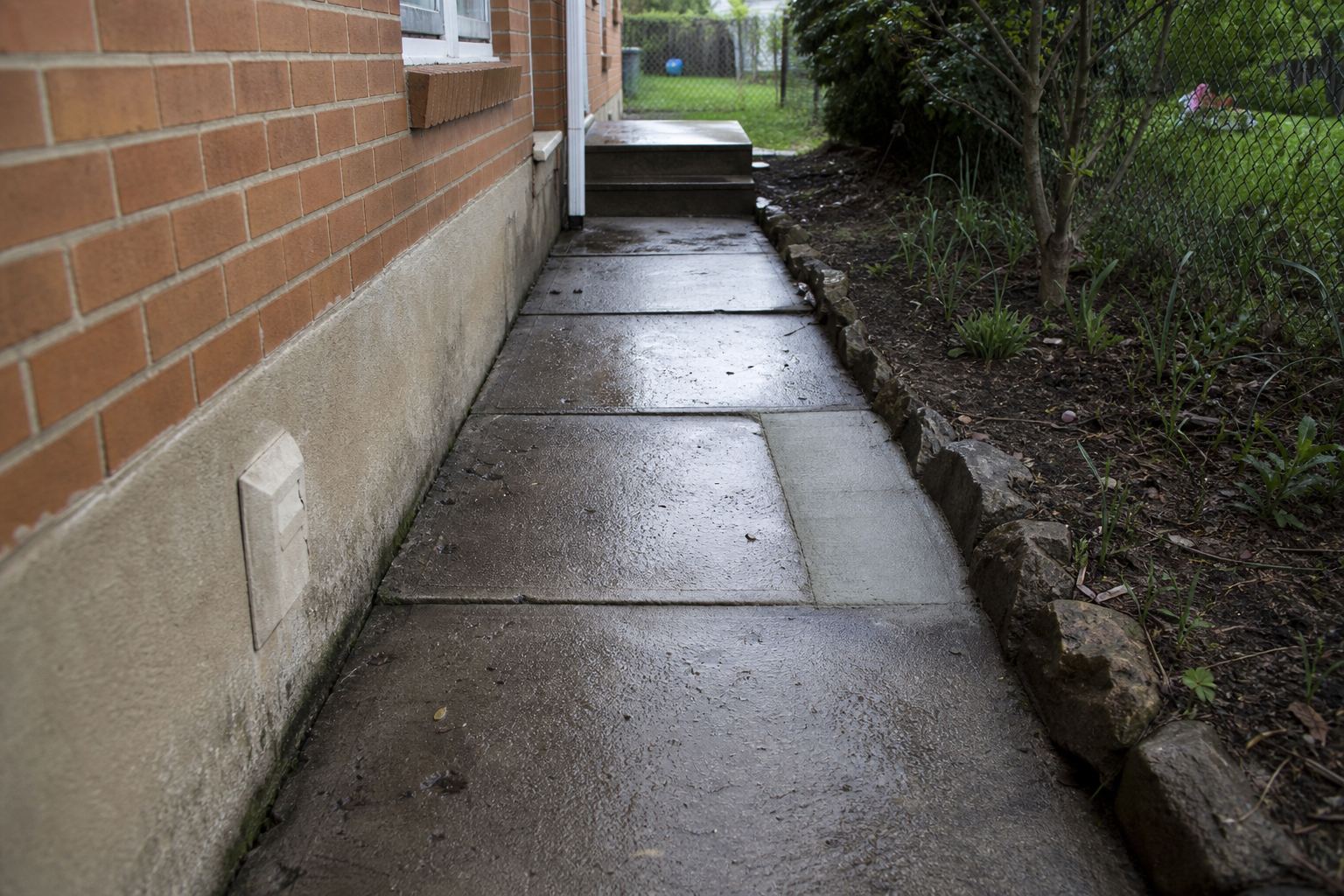Rain-darkened side walkway and compact porch steps