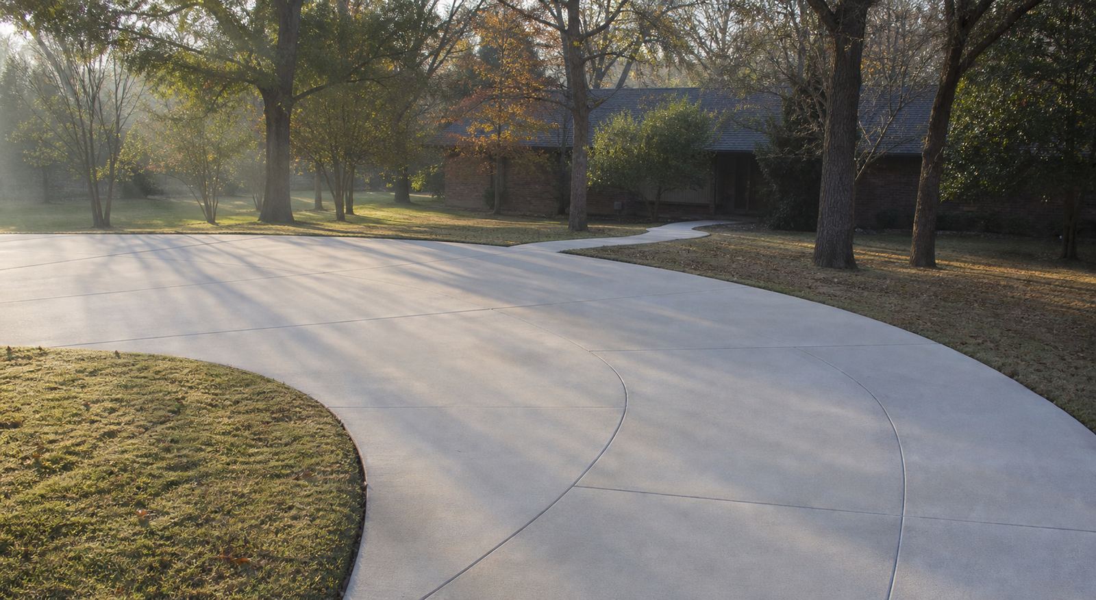 Sweeping curved residential concrete driveway at sunrise