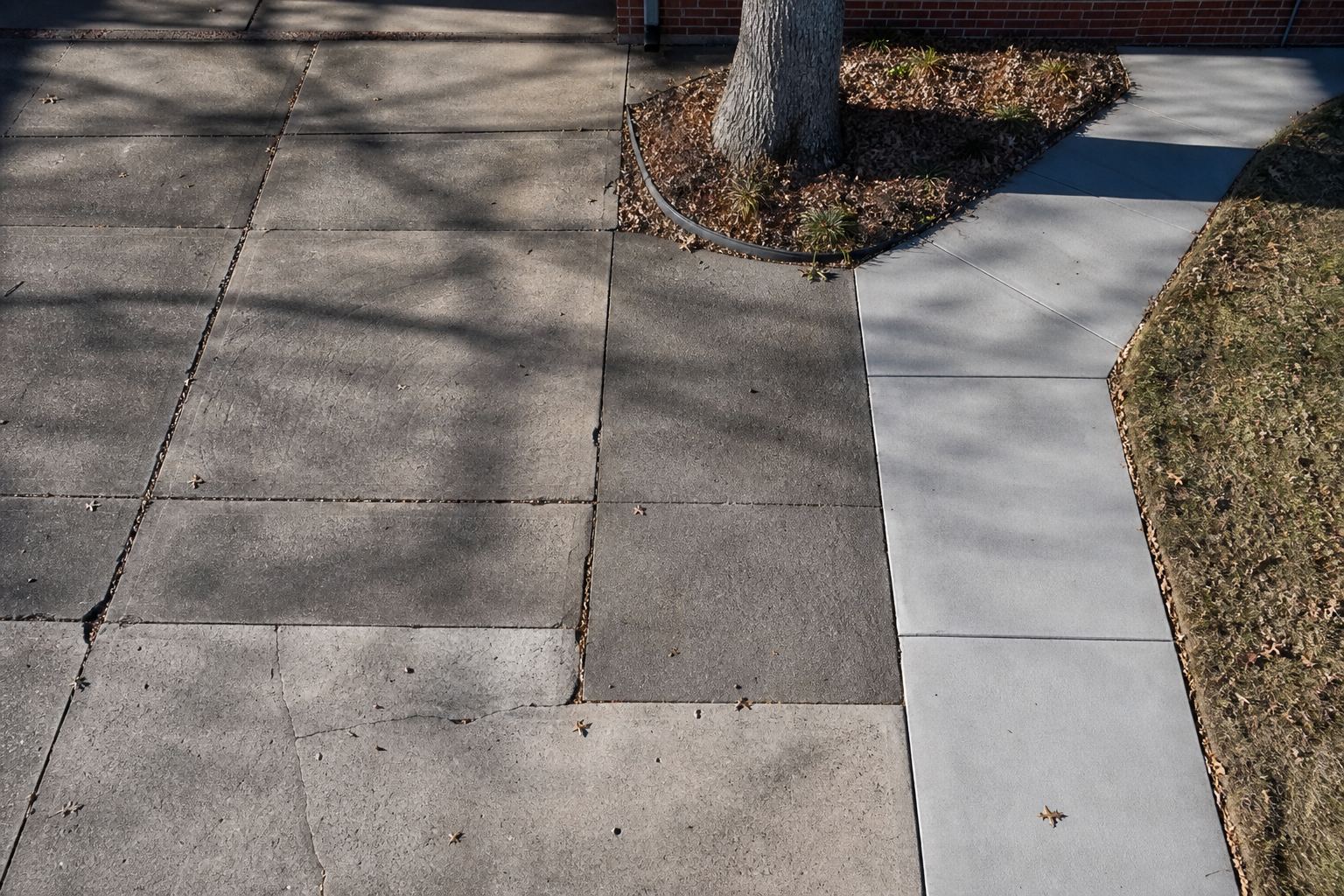 Overhead view of weathered driveway panels meeting a newer walkway